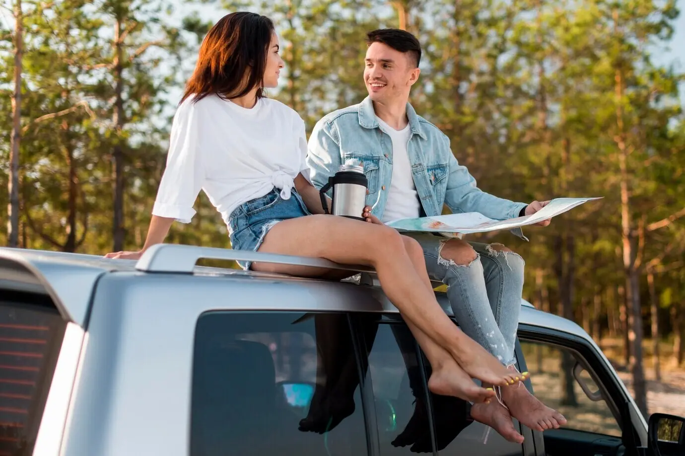 Ganzkörperaufnahme eines Paares, das auf einem Auto sitzt und eine Karte hat.